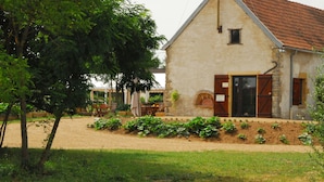 Un bâtiment rustique avec une façade en pierre, un toit recouvert de tuiles rouges et une petite fenêtre.