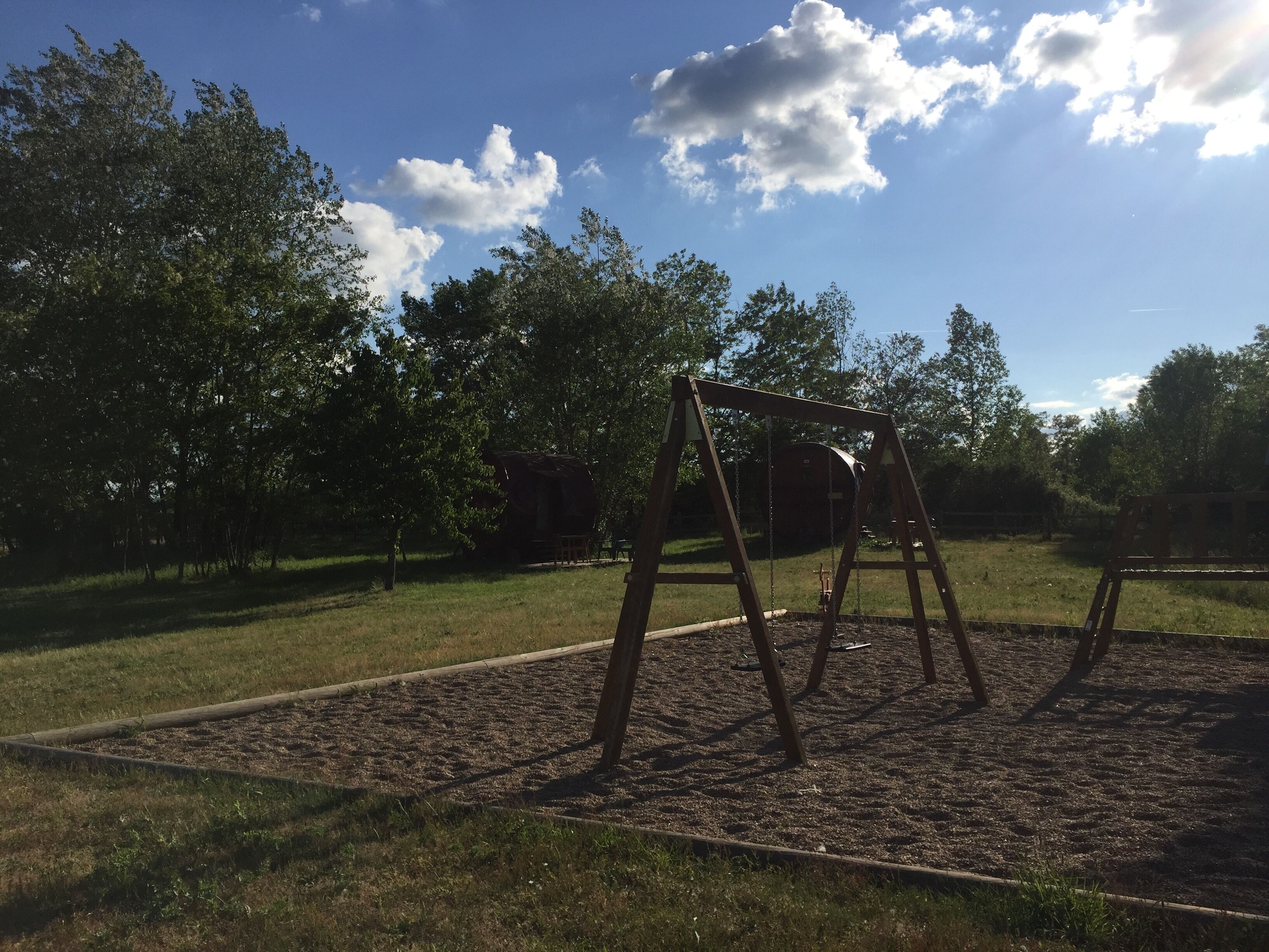 Un parque infantil con columpios y un arenero.