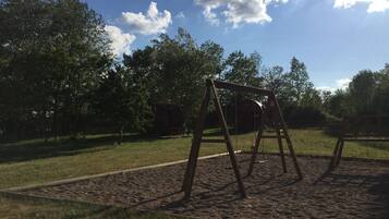 Un parque infantil con columpios y un arenero.