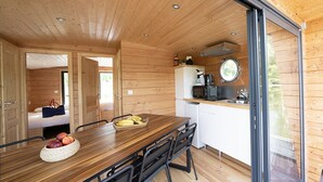 L’intérieur d’une cabane en bois comprend un coin repas, une cuisine et une porte-fenêtre coulissante qui donne sur une terrasse.