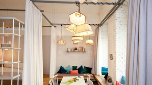 A modern interior with a white dining table, white chairs, a wooden bench, and a white brick wall. - grätzlhotel Karmelitermarkt (Vienna)