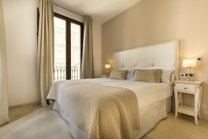 Une chambre bien rangée, avec un grand lit, deux tables de chevet équipées de lampes et une fenêtre avec des rideaux.