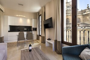 A modern hotel room with a kitchen, dining area, and a balcony with a view of historic architecture. - Siloe Plaza (Granada)