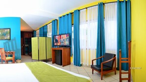 Een hotelkamer met een bed, bureau, stoel, televisie en gordijnen.
