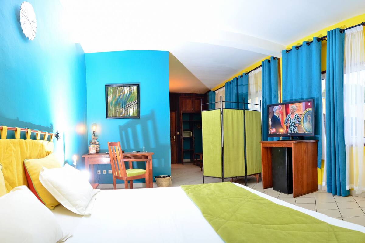 Una habitación de hotel con una cama, un escritorio, una silla, un televisor y cortinas.
