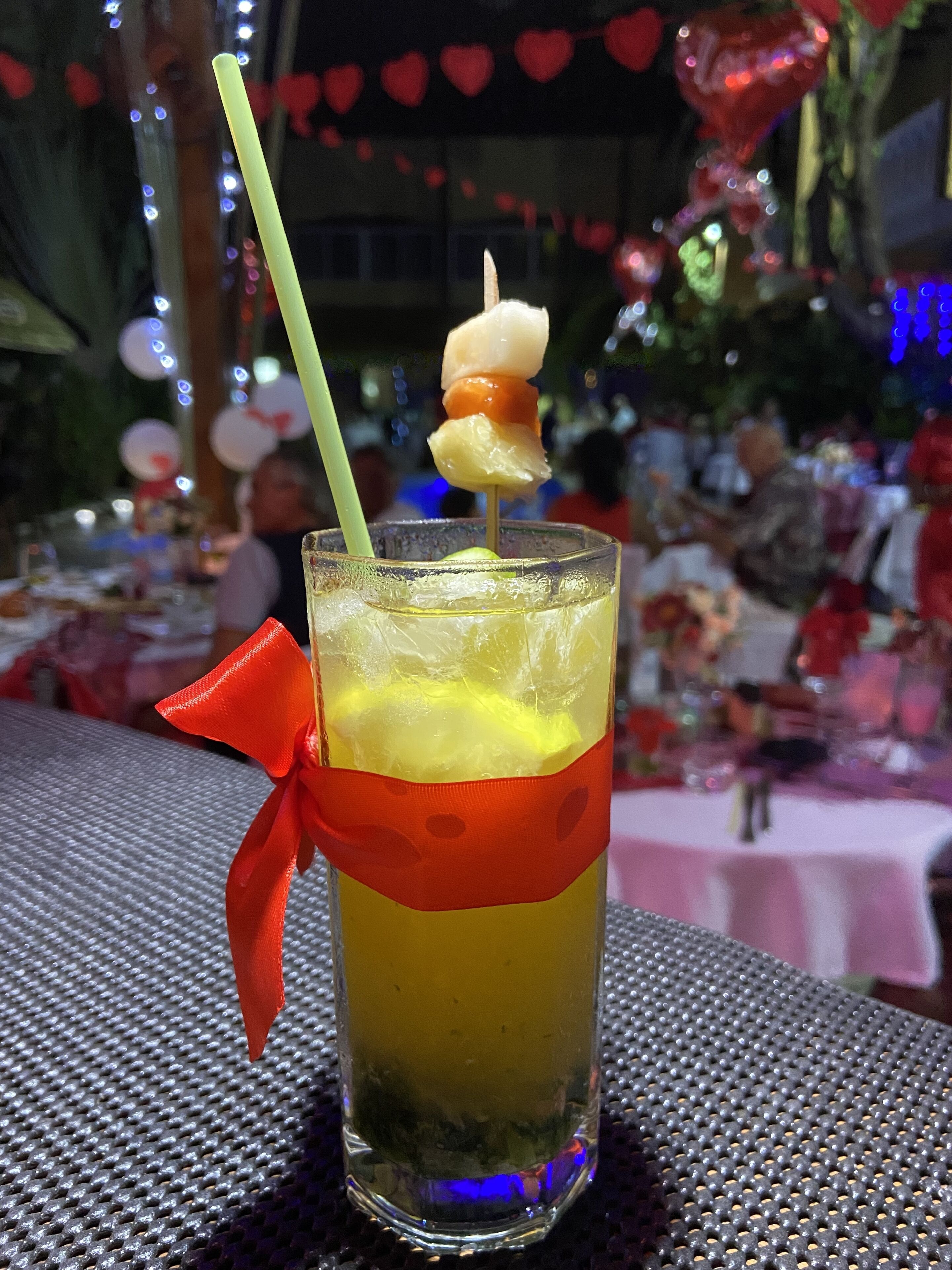 Un vaso con una bebida en capas, una pajita y un lazo decorativo.