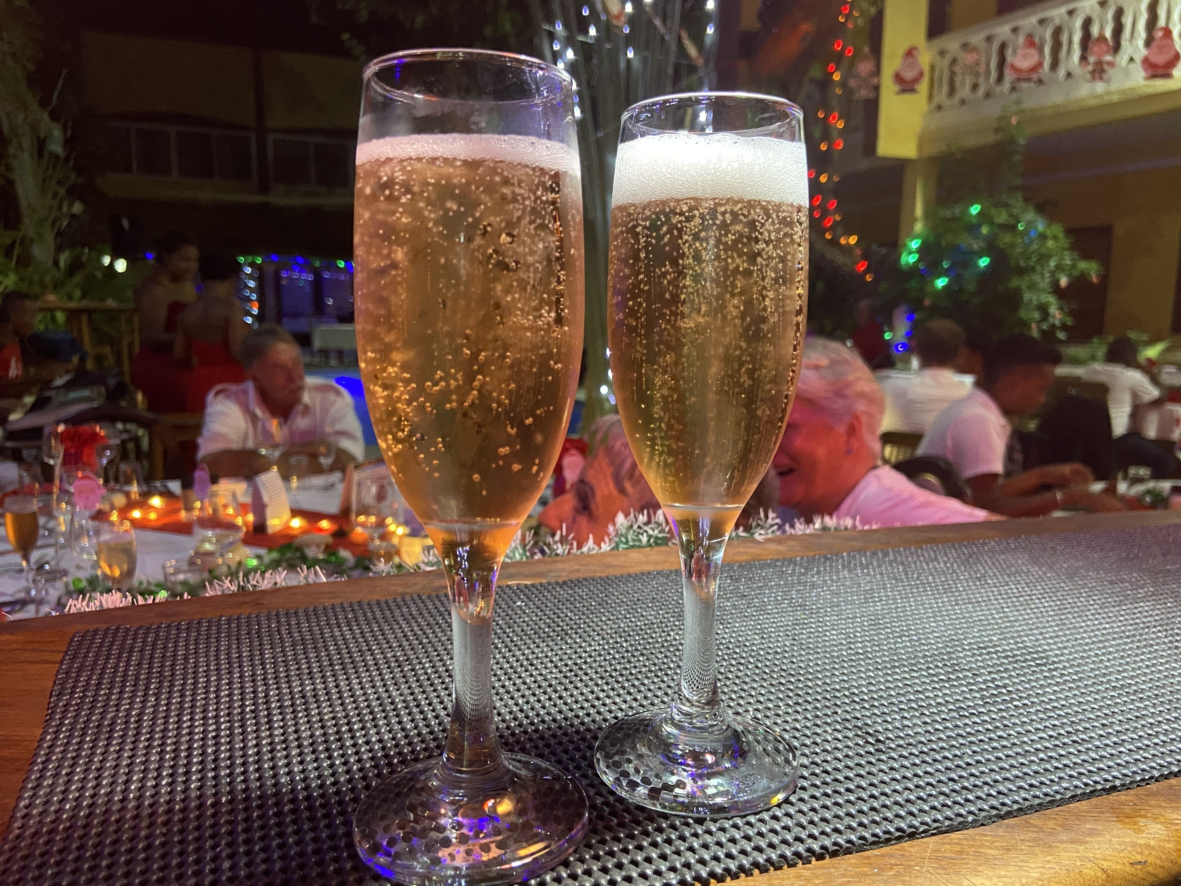 Two glasses of bubbly on a table with a textured mat.