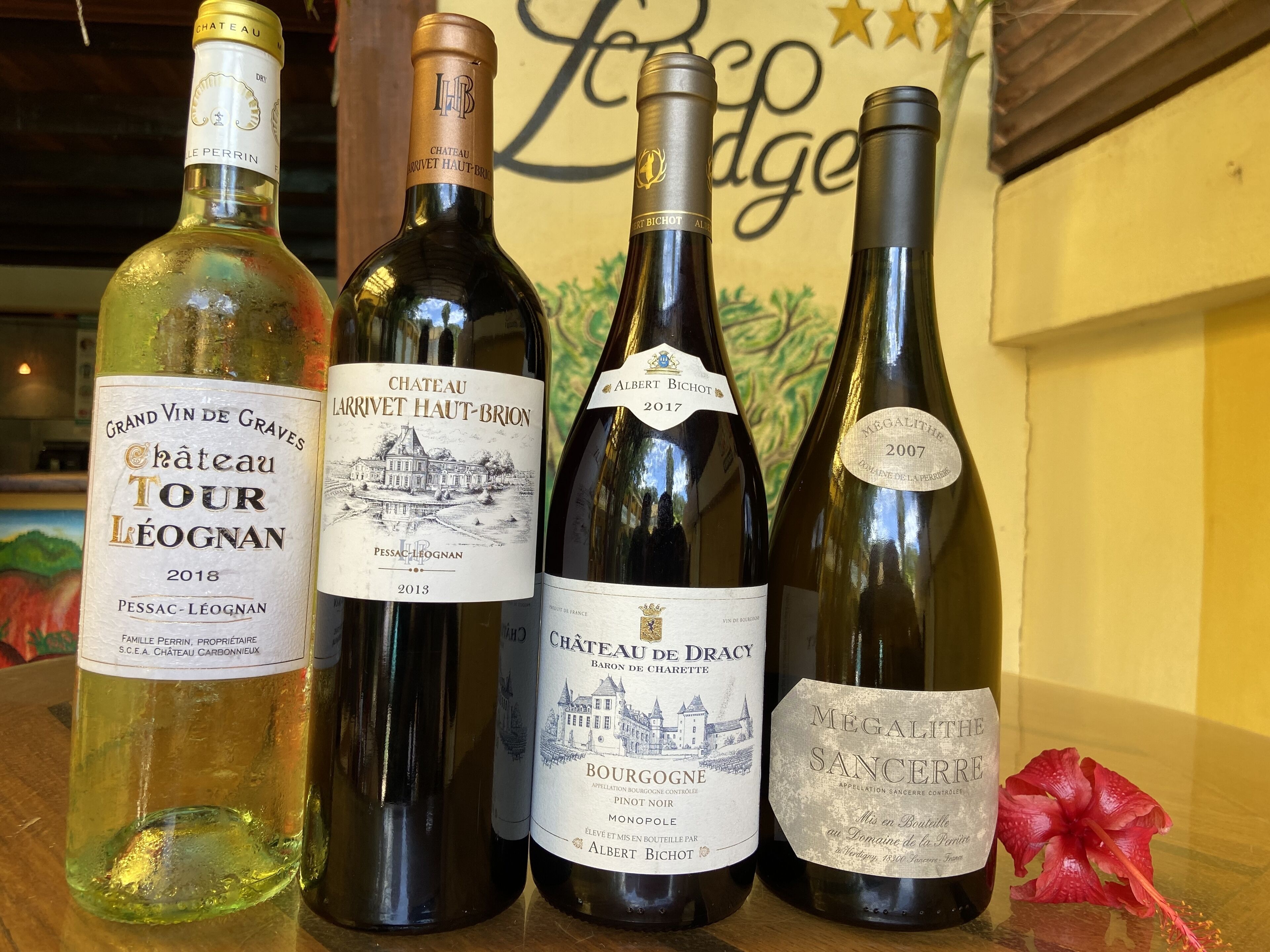 Four wine bottles on a wooden surface with a floral decoration.
