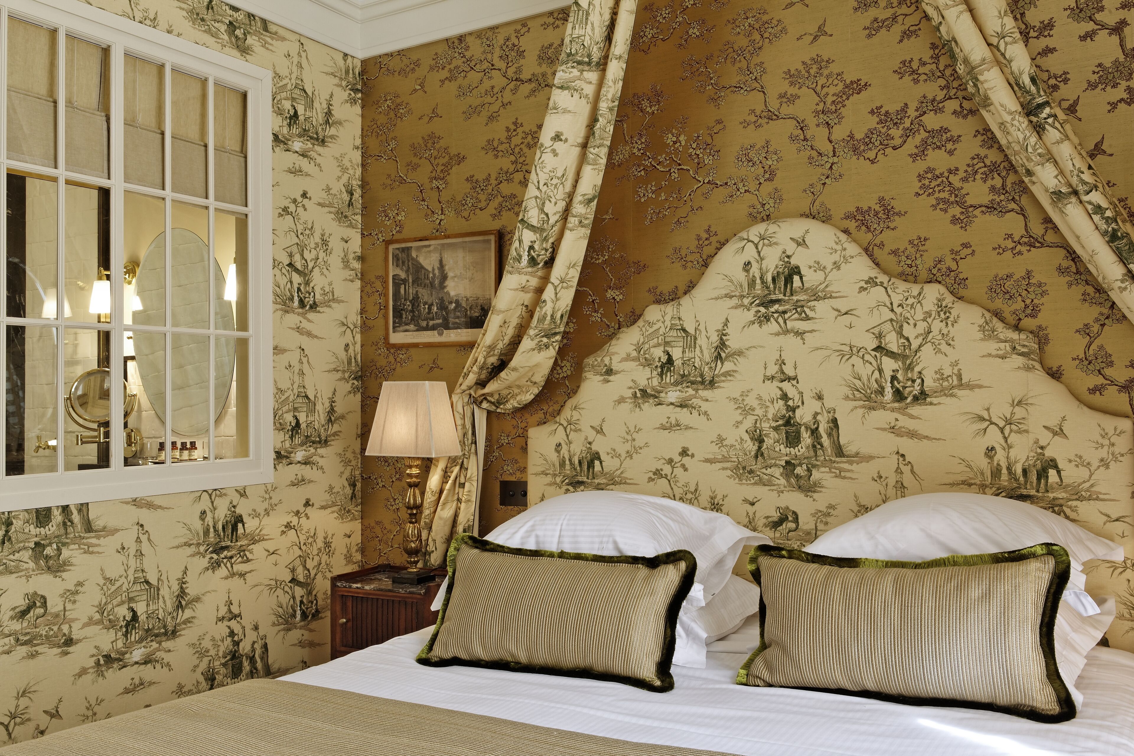 A room with a bed, a nightstand, a lamp, and a window with curtains.