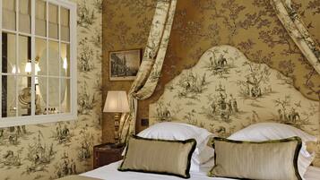 A room with a bed, a nightstand, a lamp, and a window with curtains.