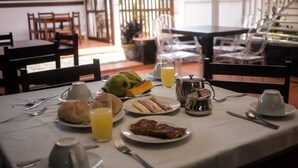 A breakfast table set with plates of food, a coffee pot, and a pitcher of juice. - Cocoa Hotel Residence São Tomé (São Tomé)