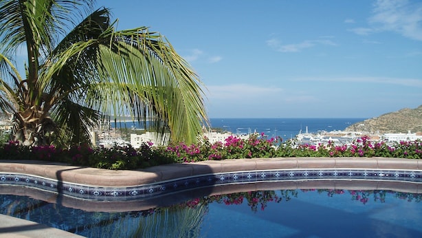 Ein Pool mit Blick auf das Meer und Gebäude im Hintergrund.