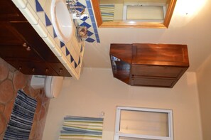 Un baño con piso de baldosas, un lavamanos, un espejo y una ventana.