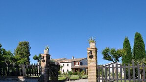 A gated property with a traditional house, a paved driveway, and a clear blue sky.