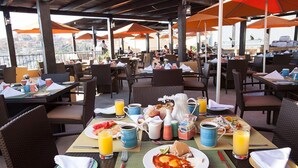 An outdoor dining area with tables and chairs, umbrellas, and a view of the city. - Casa Diamond (Cabo San Lucas)