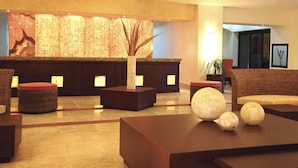 A modern lobby with a reception desk, seating area, and decorative elements. - Casa Diamond (Cabo San Lucas)
