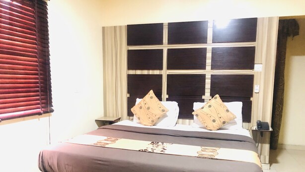 Een hotelkamer met een groot bed, nachtkastje en een raam met zonwering.