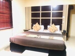 Ein Hotelzimmer mit einem großen Bett, einem Nachttisch und einem Fenster mit Jalousien.