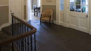 A spacious foyer with a grand chandelier, a wooden staircase, and a view into a dining area. - Haddington Place (Edinburgh)
