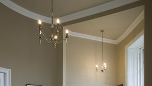 A dining area with a wooden table and chairs, a chandelier, and a kitchen in the background. - Haddington Place (Edinburgh)