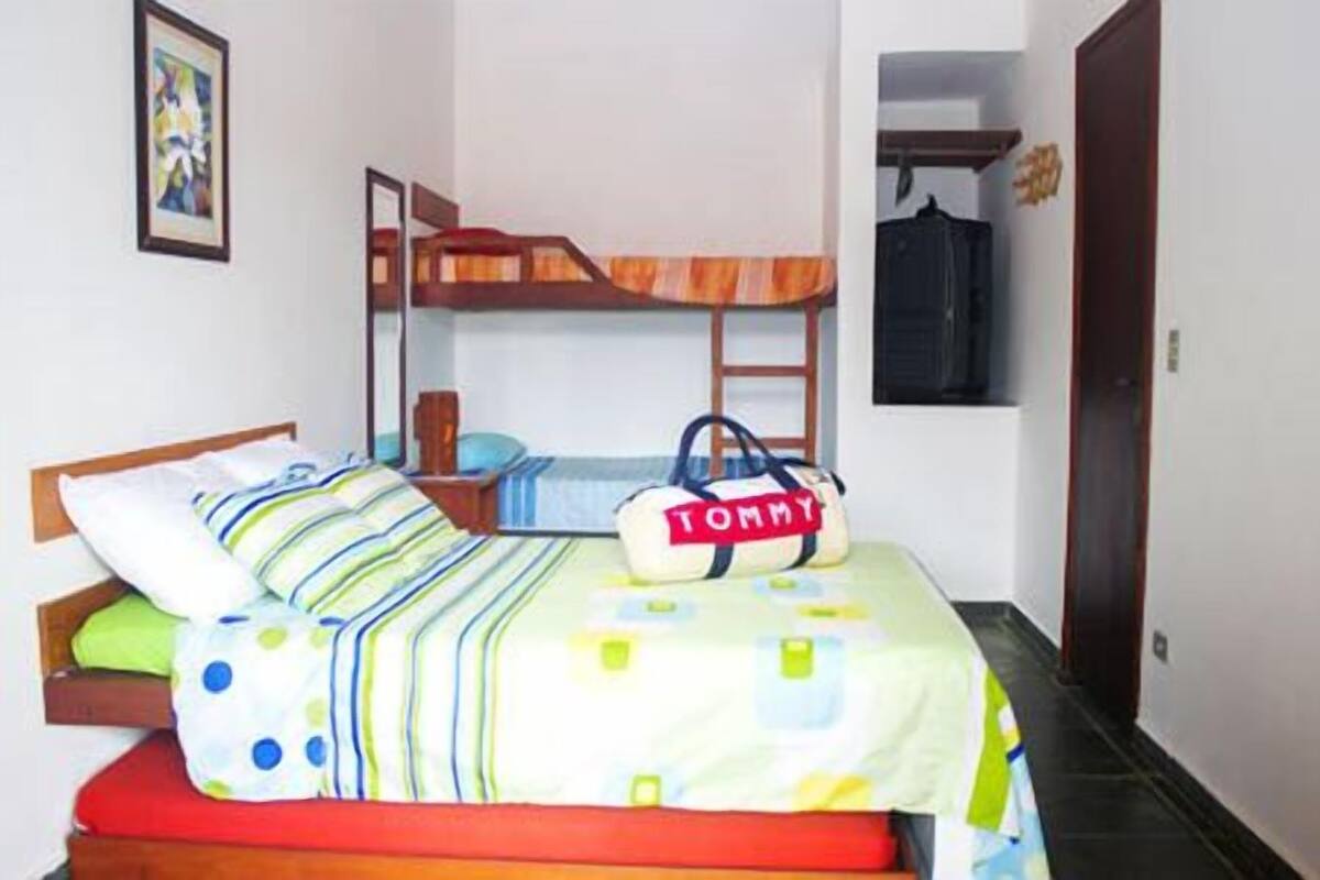 Una cama litera con un edredón a rayas y una bolsa Tommy en la parte superior.