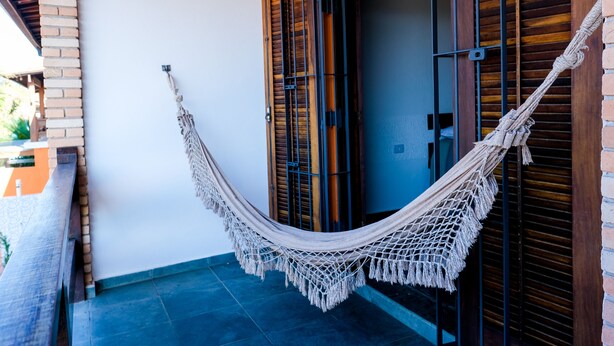 A hammock hanging between two wooden doors with a brick wall and a tiled floor. - Serramar Flat (Ubatuba)