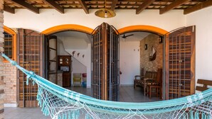 A hammock in a covered outdoor area with a brick wall and wooden beams. - Serramar Flat (Ubatuba)