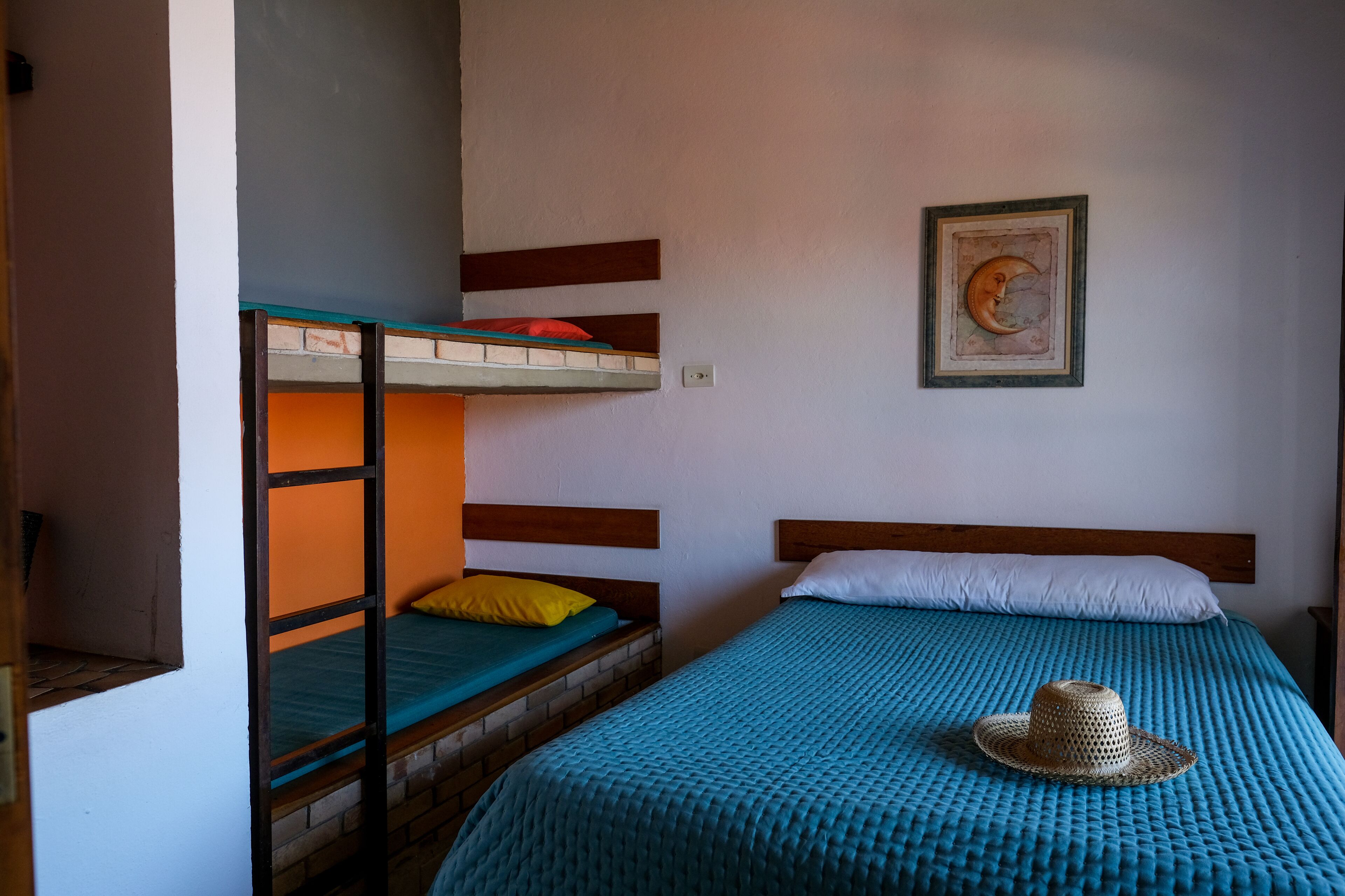 A room with bunk beds, a single bed, and a wall-mounted picture.