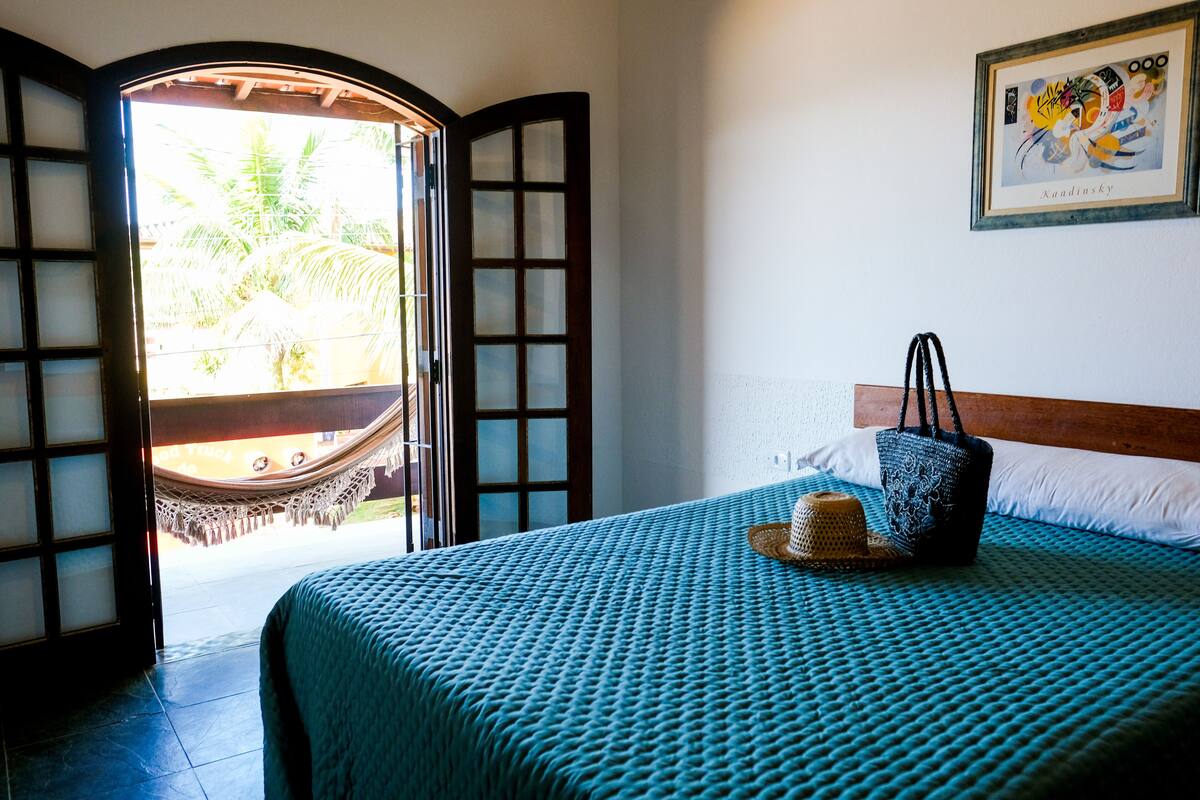 Una habitación con cama, hamaca y vistas a palmeras.