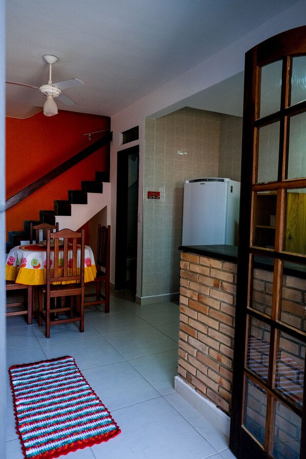 A kitchen with a refrigerator, a wooden table with chairs, and a staircase.