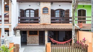 A two-story house with a tiled roof, a wooden balcony, and a hammock. - Serramar Flat (Ubatuba)
