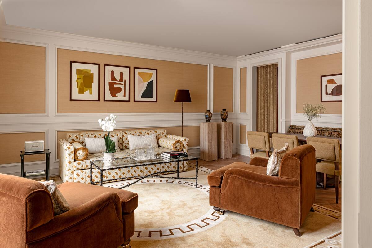 Una sala de estar con un sofá estampado, dos sillones, una mesa de centro y un comedor con sillas y una mesa.
