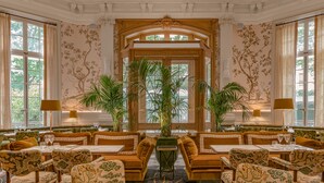 Un comedor formal con decoración elaborada, disposición de mesas y amplias ventanas.