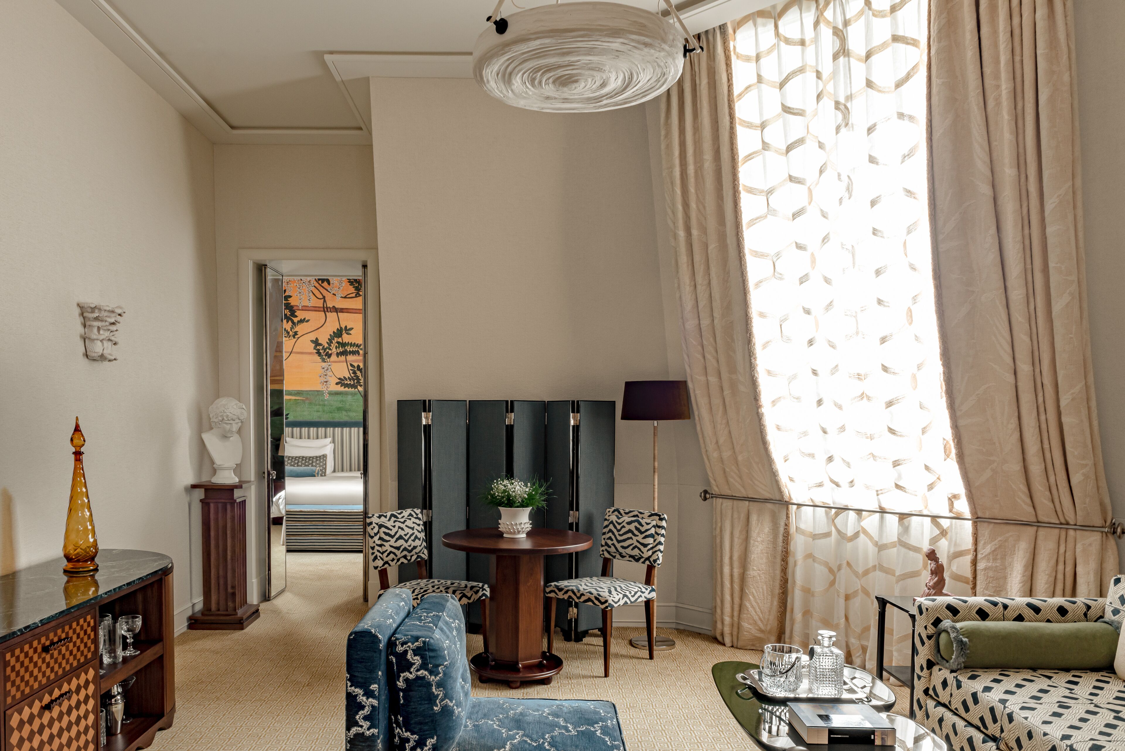 Ein Zimmer mit einer Couch, Stühlen, einem Tisch mit einer Vase und einer Lampe.