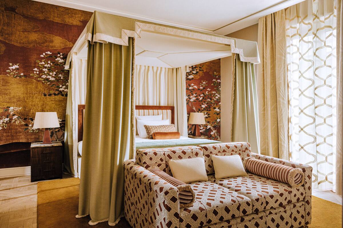 Un dormitorio con una cama con dosel, un sofá cama y un sofá estampado.
