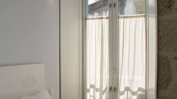Ein Schlafzimmer mit Bett, Kleiderschrank und einem fenster mit Vorhängen.