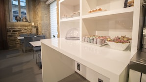 Eine moderne Küche mit weißen Arbeitsplatten, einer Steinwand und einer Essecke mit Tisch und Stühlen.