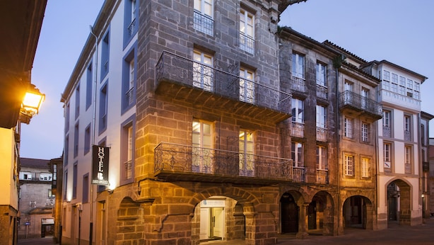 Ein historisches Gebäude mit mehreren Balkonen und rundbogigen Hauseingängen, vermutlich ein Hotel oder ein öffentliches Gebäude.