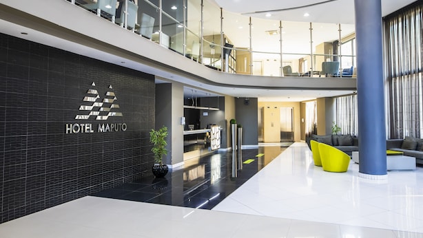 A modern hotel lobby with a reception desk, seating area, and a staircase leading to an upper level. - WL Hotel Maputo City Centre Mozambique Collection (Maputo)