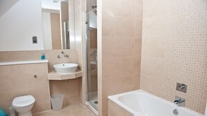 A modern bathroom with a toilet, sink, shower, and bathtub. - The Mill House (Earlston)
