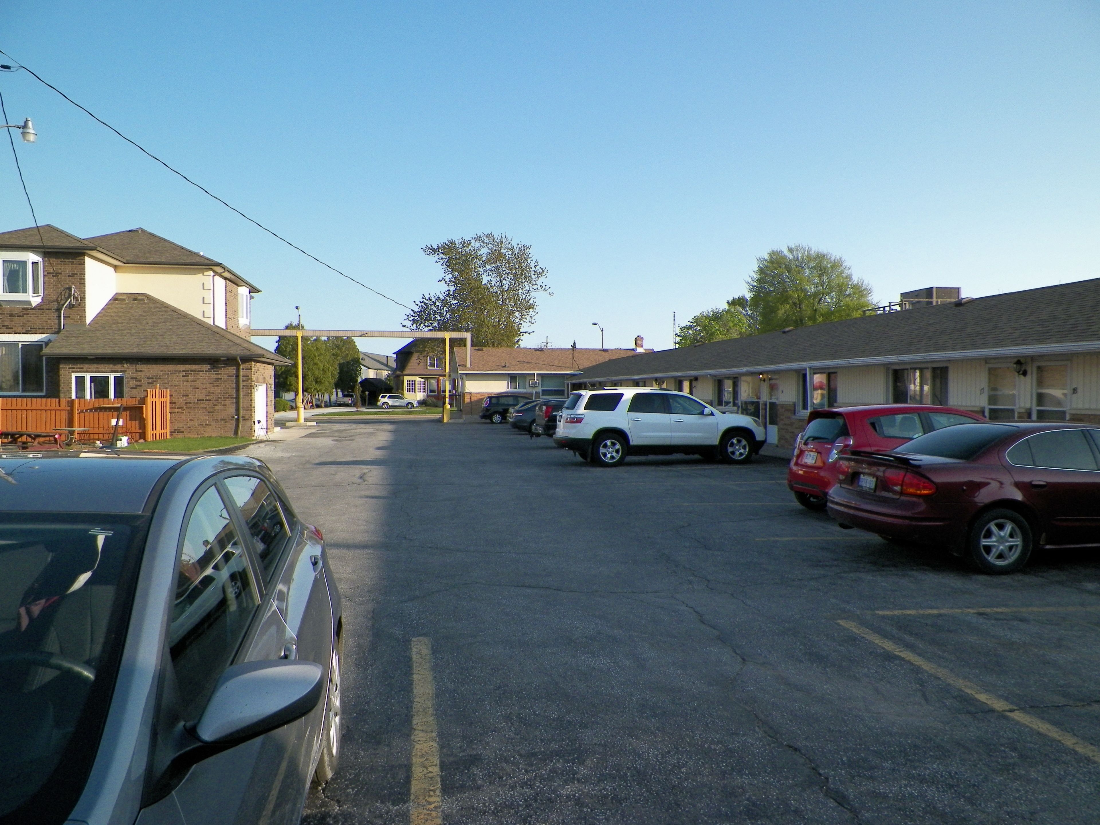 A parking lot with several cars, a building with a sign, and a clear sky.