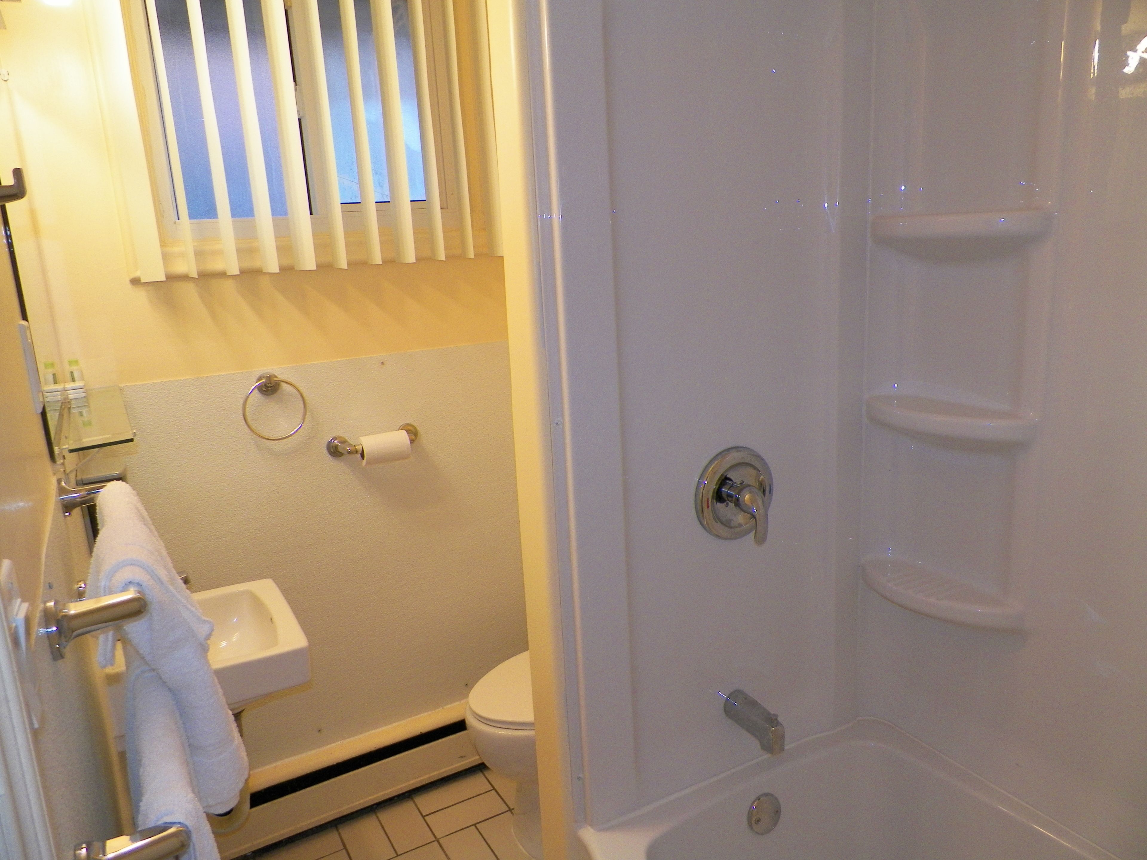 A bathroom with a toilet, sink, and shower stall.