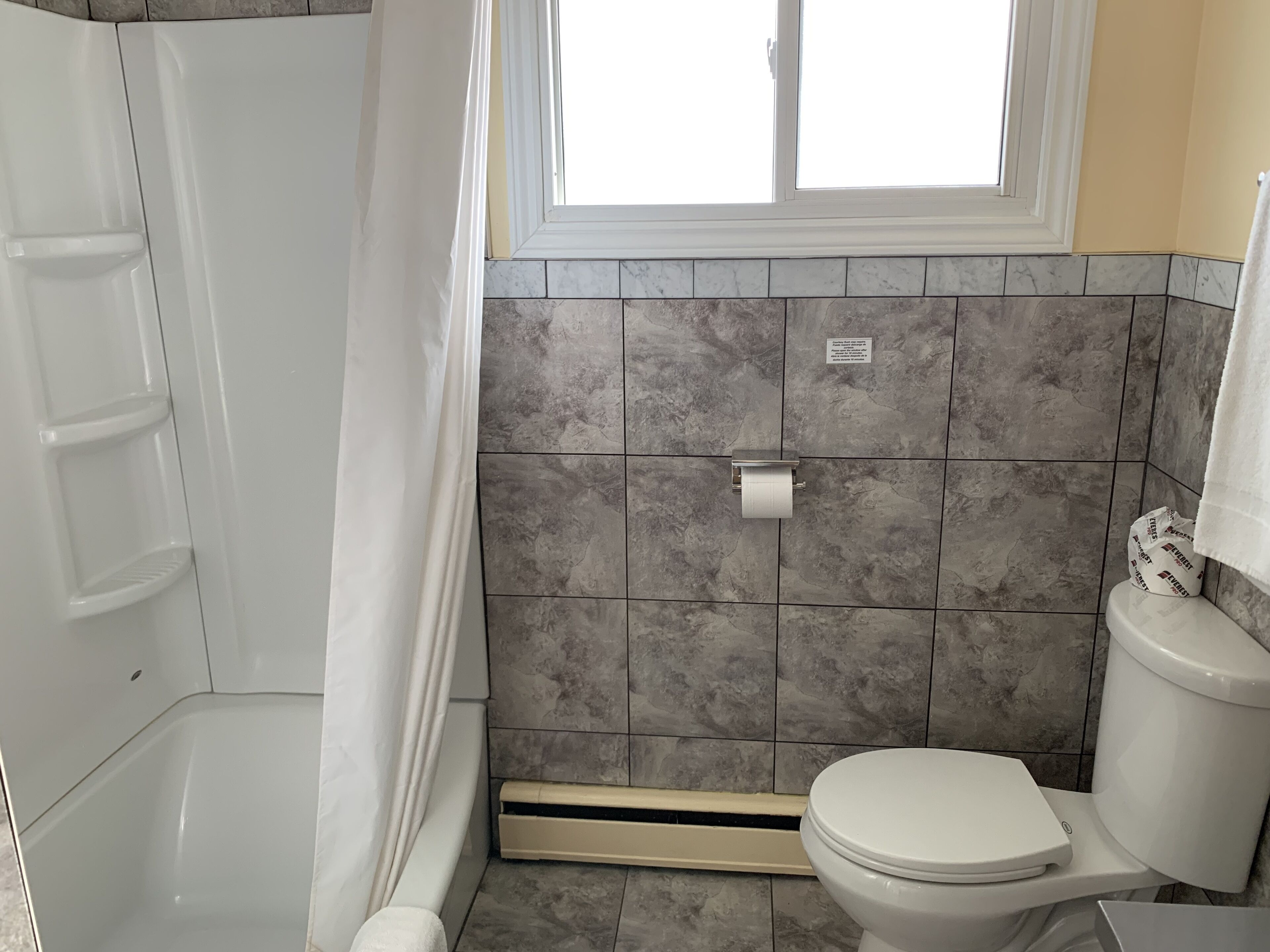Et badeværelse med badekar, toilet og bruseforhæng.