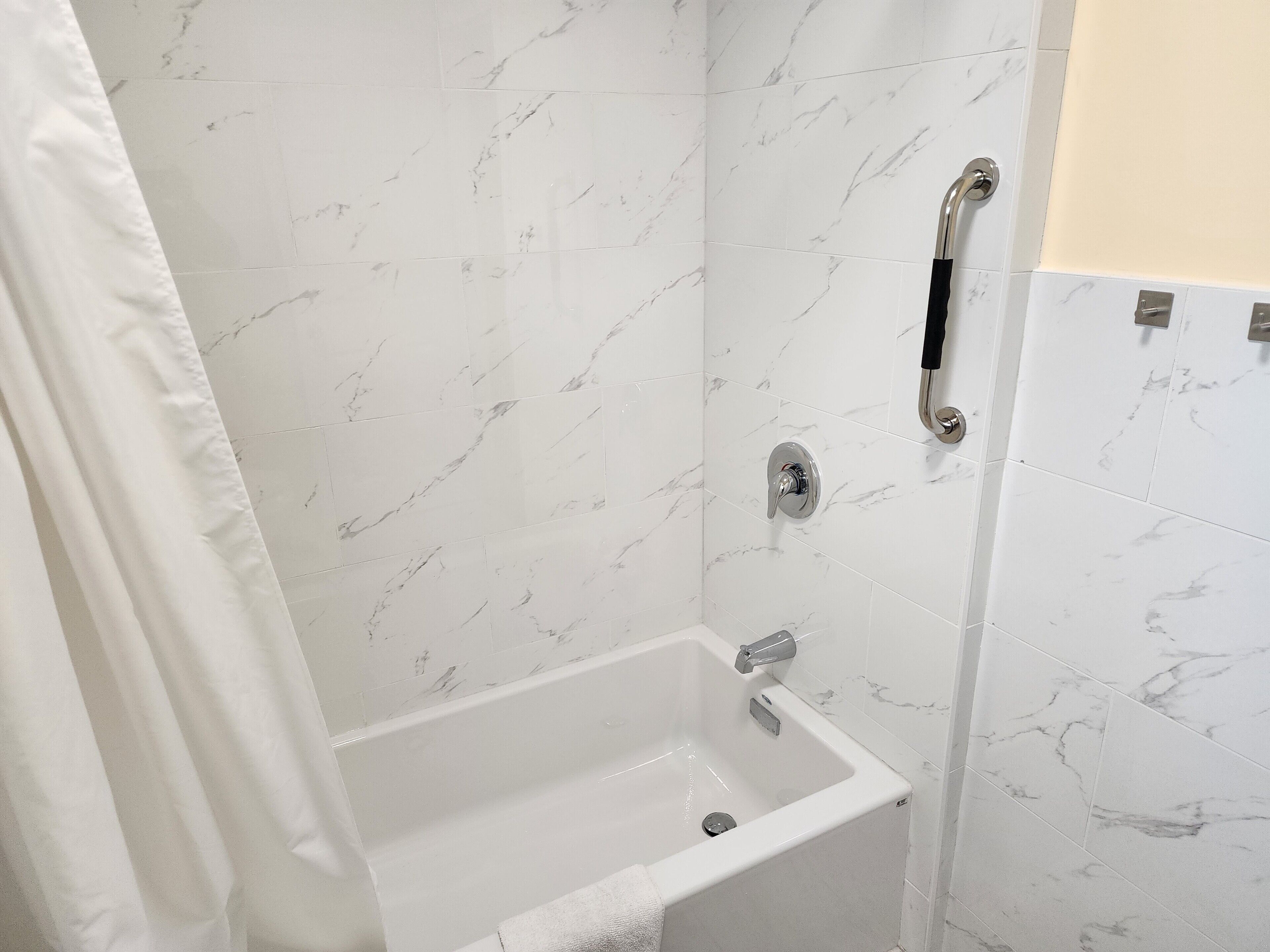 Un baño con bañera blanca, ducha y retrete.