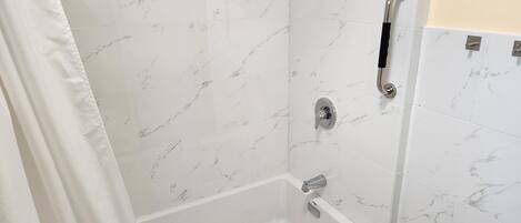 Un baño con bañera blanca, ducha y retrete.