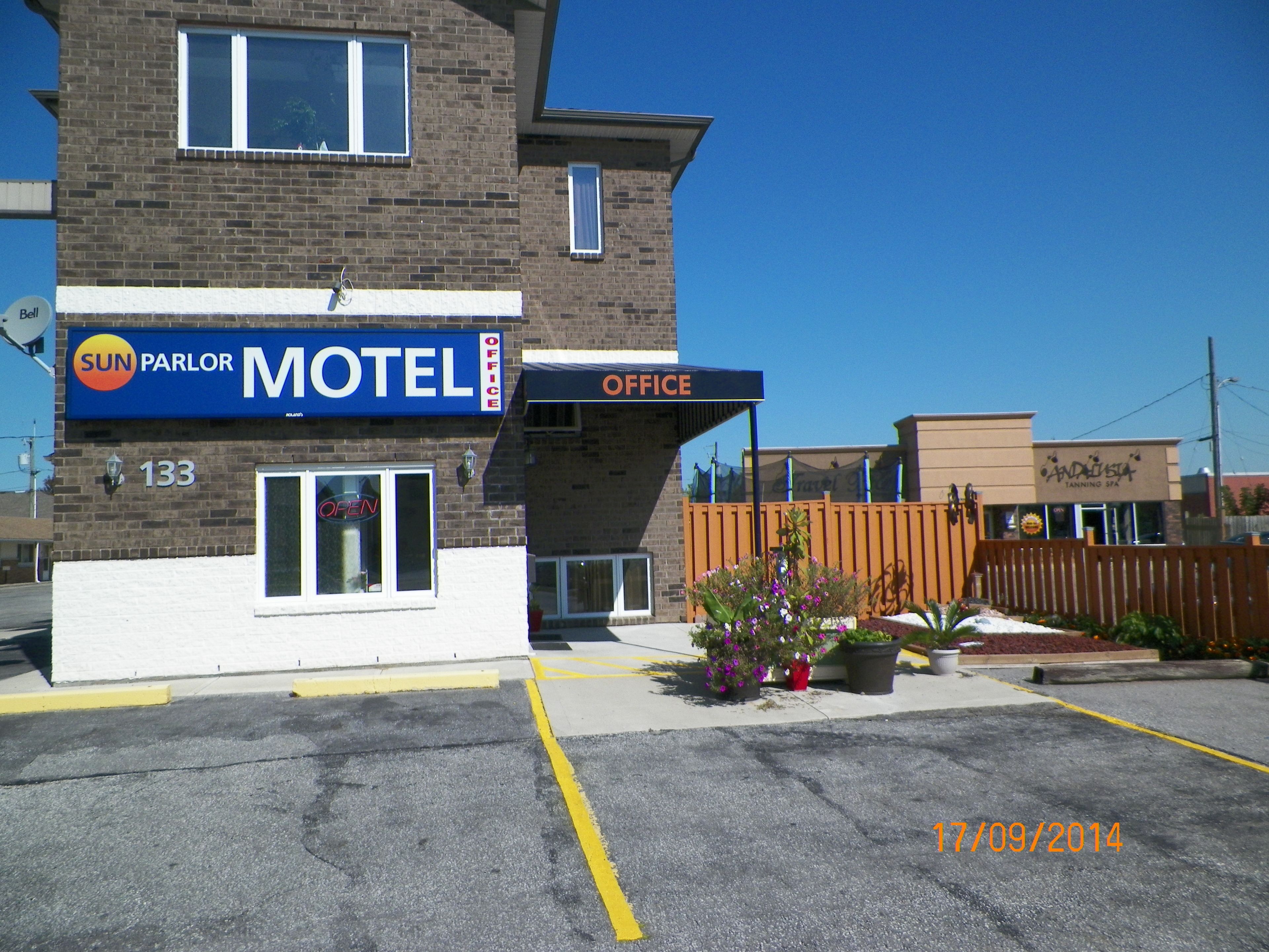 A motel with a blue sign, an office, and a parking lot.
