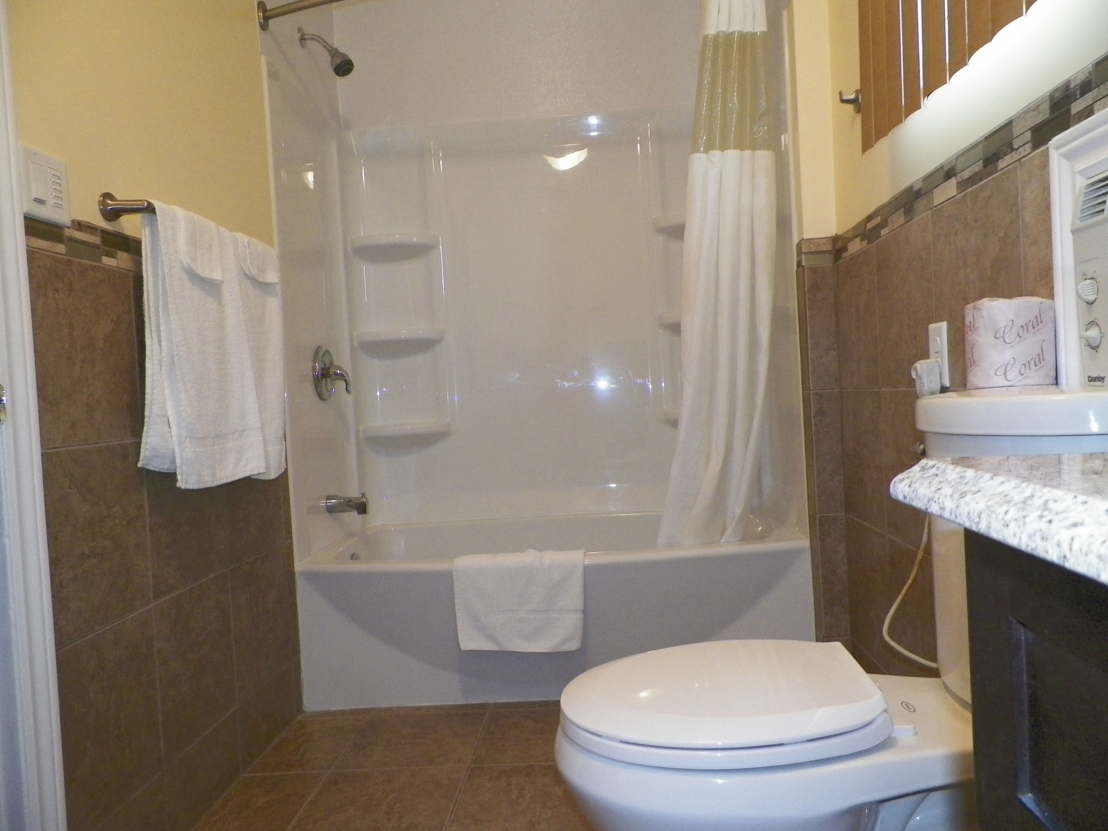 A bathroom with a bathtub, toilet, and shower curtain.