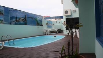 Una piscina al aire libre, sillones reclinables de piscina
