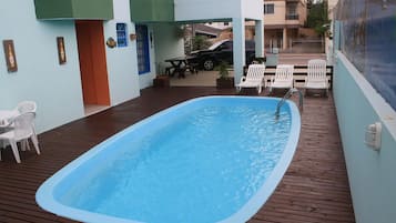 Una piscina al aire libre, sillones reclinables de piscina