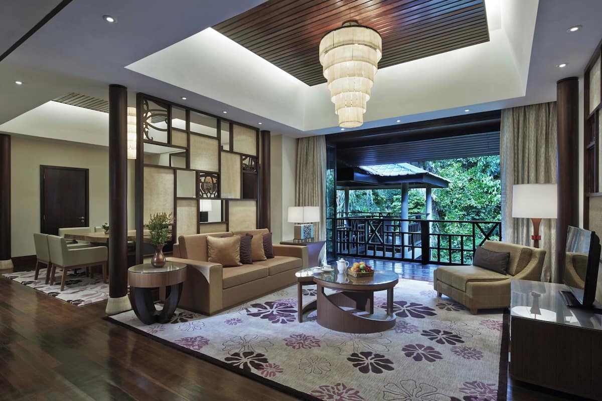 A modern hotel lobby with a sofa, coffee table, and dining area.